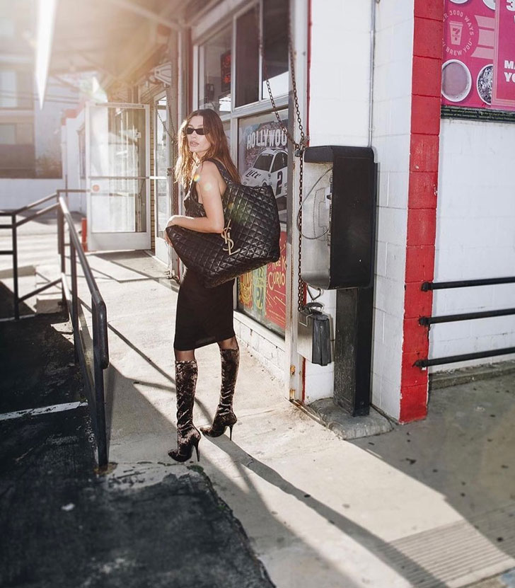 Девушка в платье и сапогах с черной большой сумкой от Saint Laurent