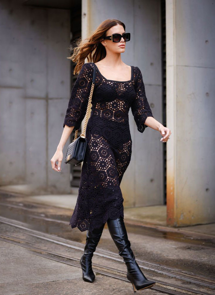 Девушка в черном кружевном платье миди и кожаных сапогах на шпильке