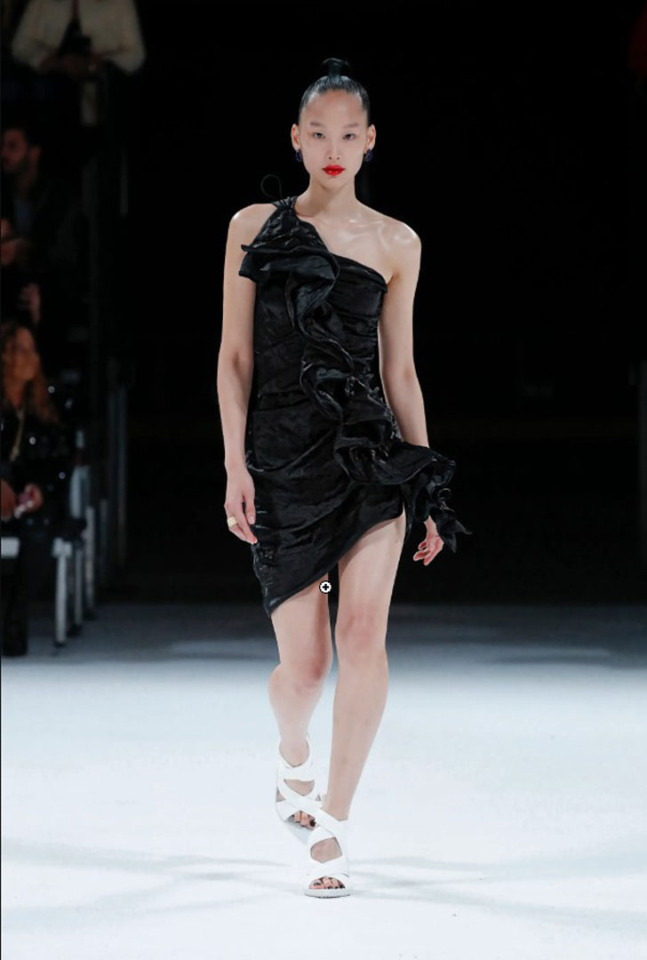 Модель в черном мини платье на одно плечо от Bottega Veneta