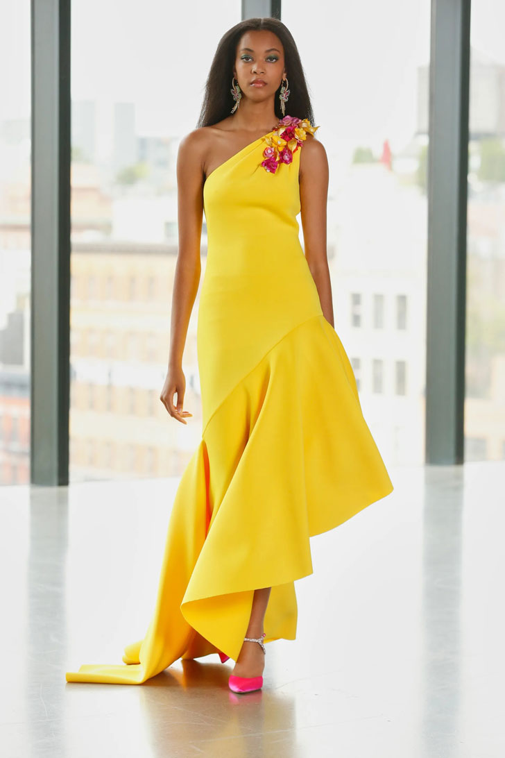 Модель в желтом длинном платье на одно плечо с воланами и розовых туфлях от Badgley Mischka