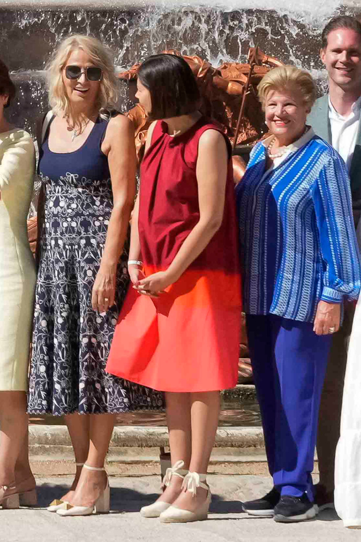 Женщина в летнем красном платье и эспадрильях на королевском приеме