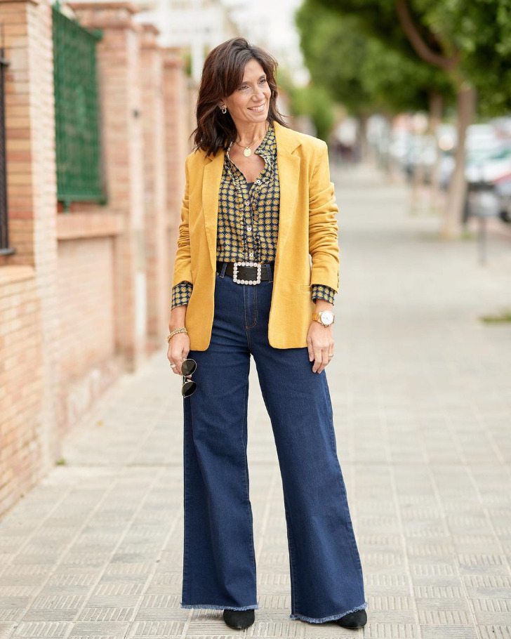 Женщина в широких джинсах, элегантном горчичном пиджаке и стильной прической