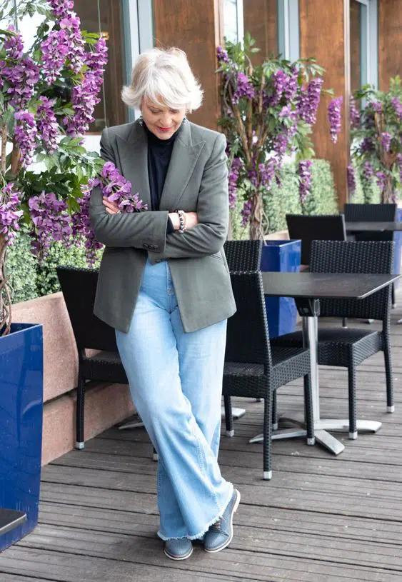 Женщина в мешковатых джинсах, пиджаке и черной водолазке