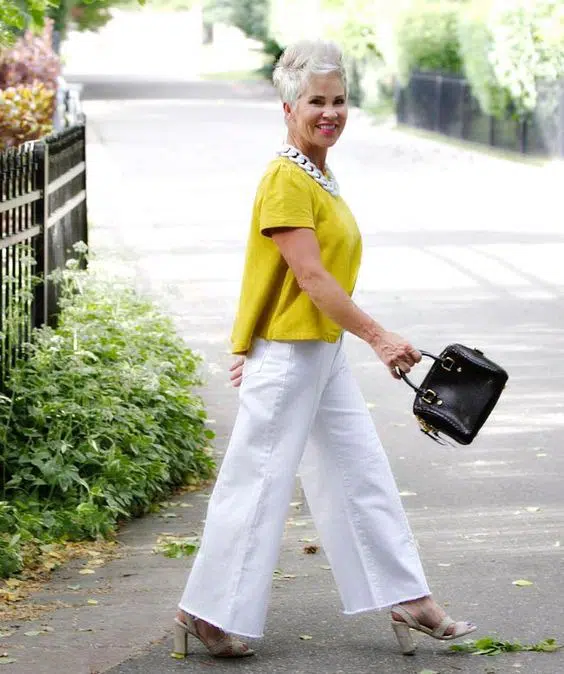 Женщина в белых широких джинсах, желтой блузке и стрижкой пикси