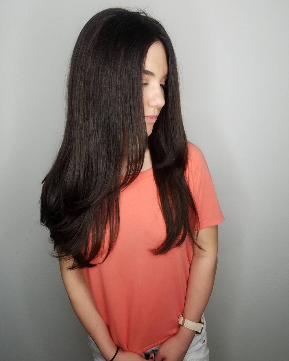 Девушка с длинной многослойной стрижкой на темных блестящих волосах