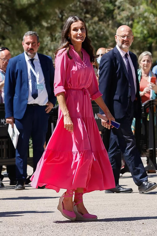 Королева Летиция в длинном розовом платье с поясом на талии и босоножках на танкетке