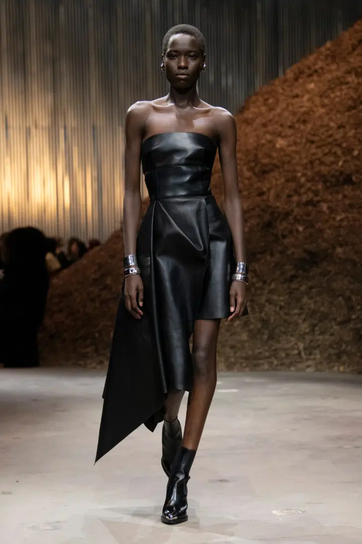 Модель в черном кожаном платье с асимметричным подолом от Alexander McQueen