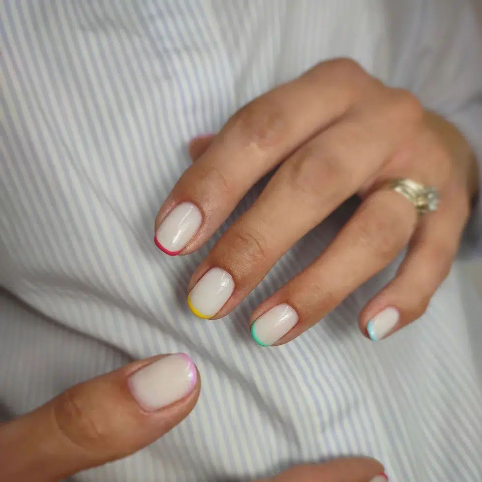 Молочный маникюр с разноцветным тонким френчем на коротких овальных ногтях