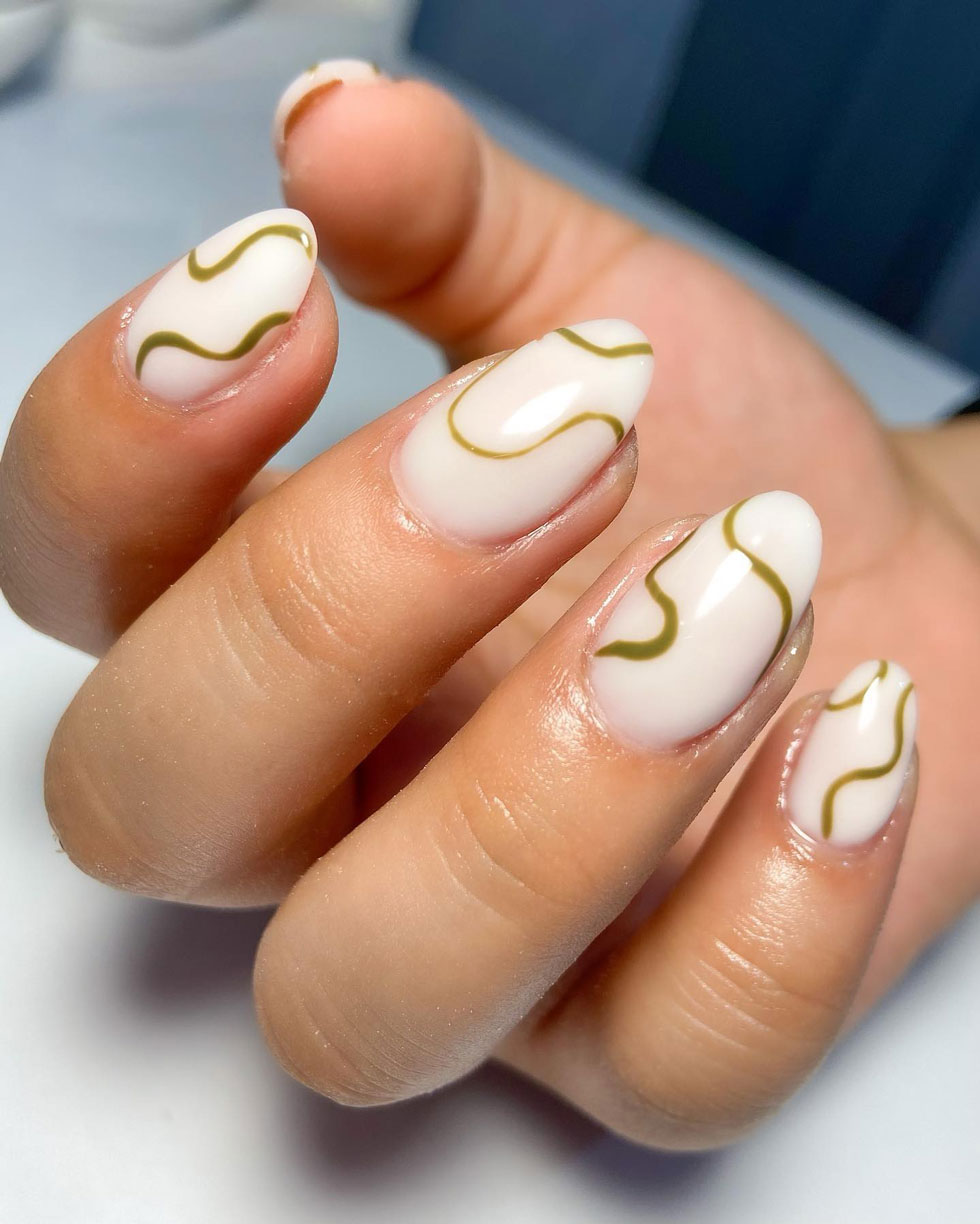 Молочный маникюр с золотыми волнами на миндальных ногтях средней длины