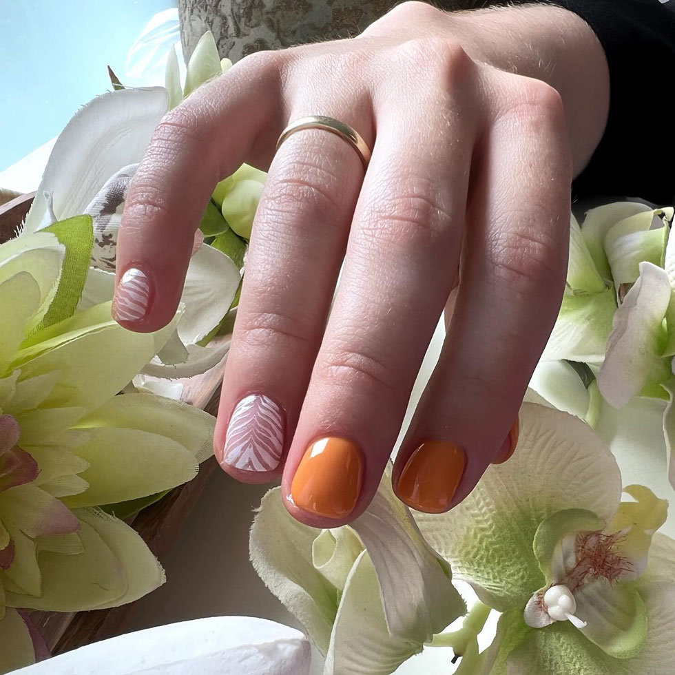 Оранжевый маникюр с белым узором на коротких натуральных ногтях