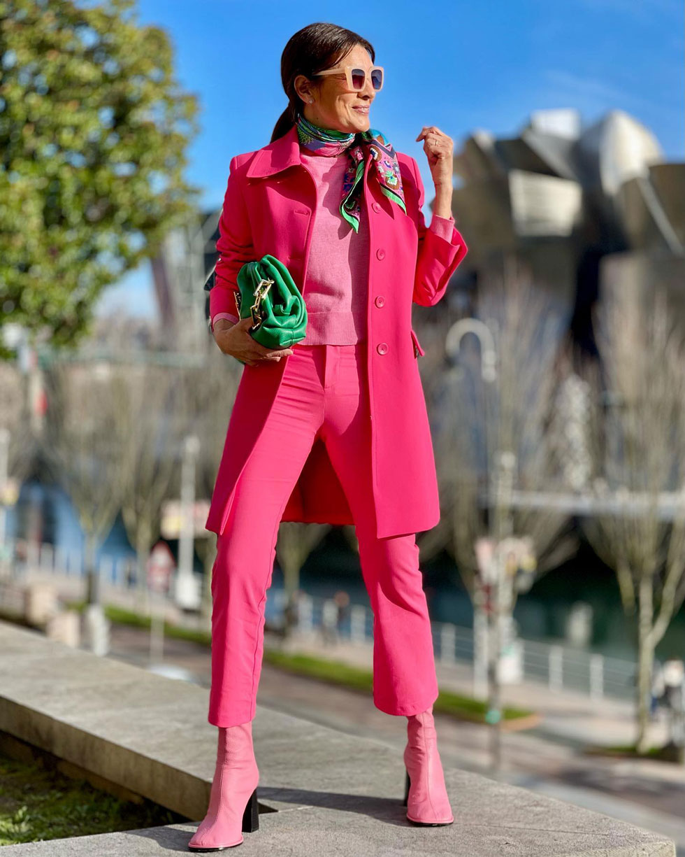 Женщина в розовом тотал-луке с цветным платком на шее