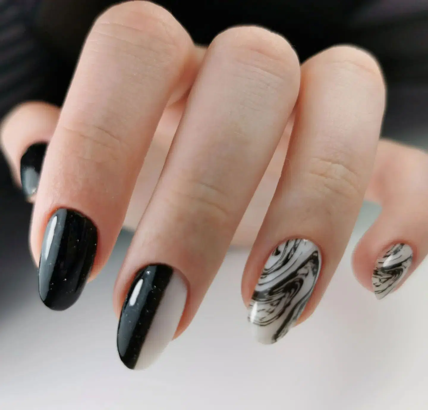 Черный маникюр с мраморным принтом на овальных ногтях средней длины