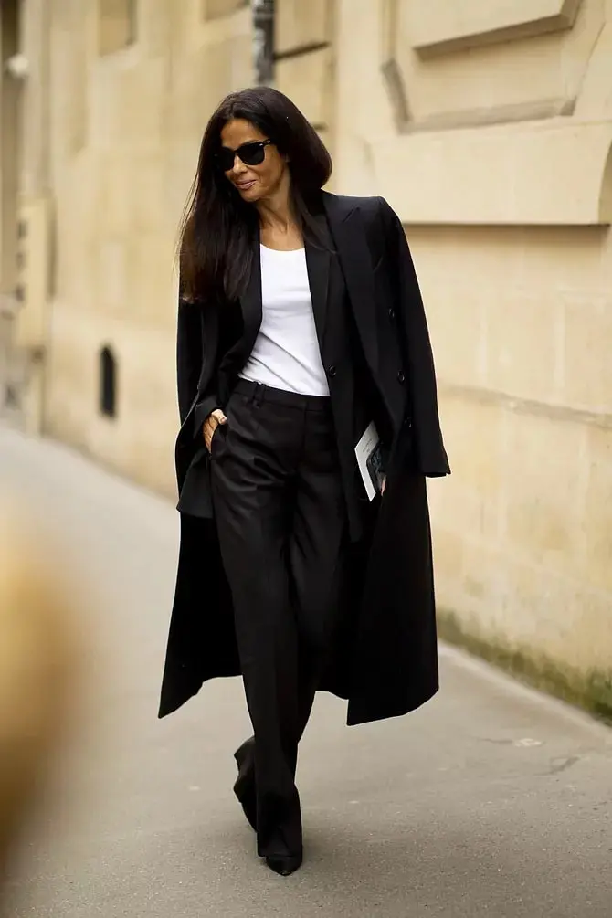 Девушка в кожаных брюках, белом топе и черном классическом пальто