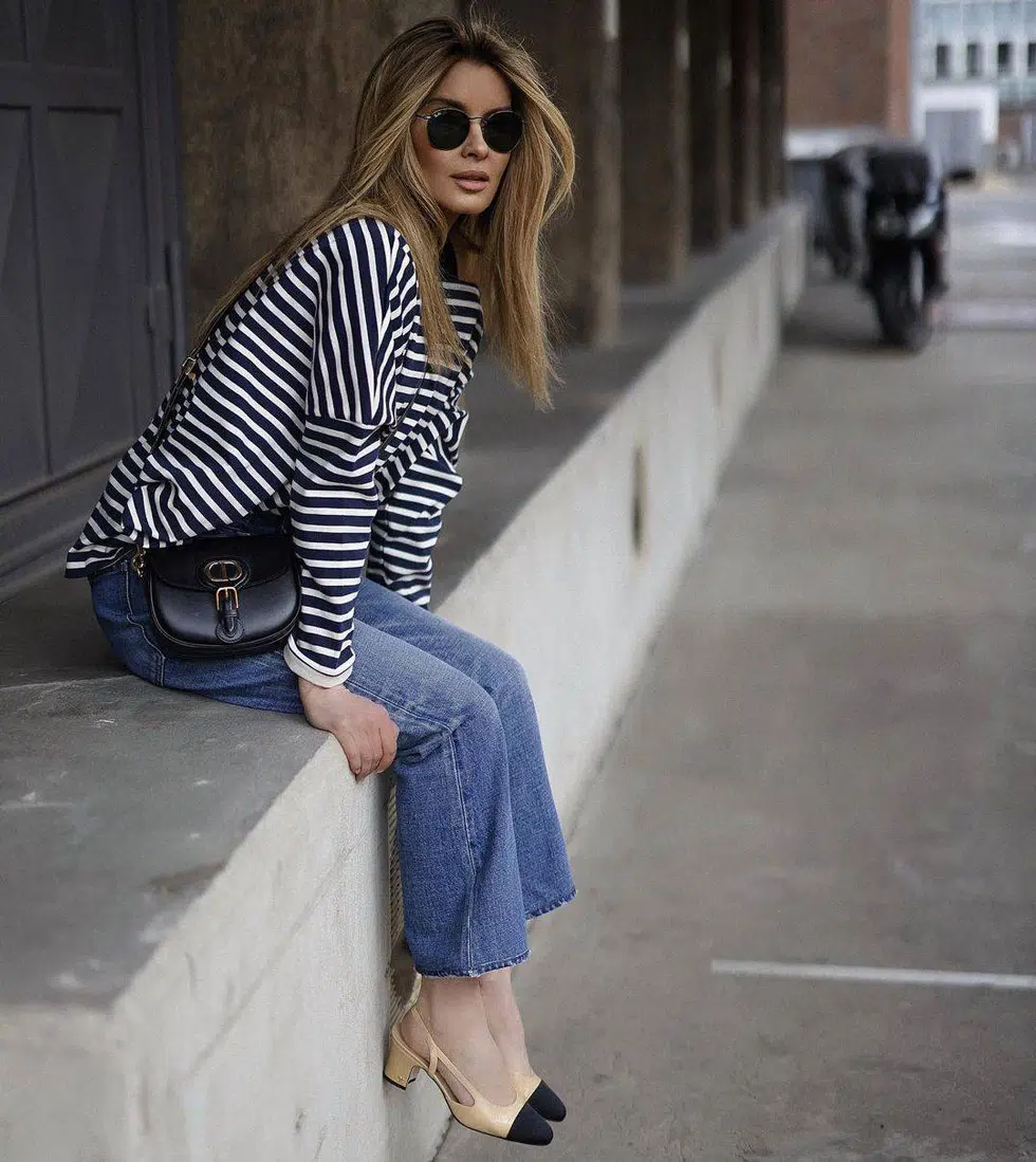 Женщина в прямых джинсах, свитшоте в полоску и двухцветных туфлях на низком каблуке
