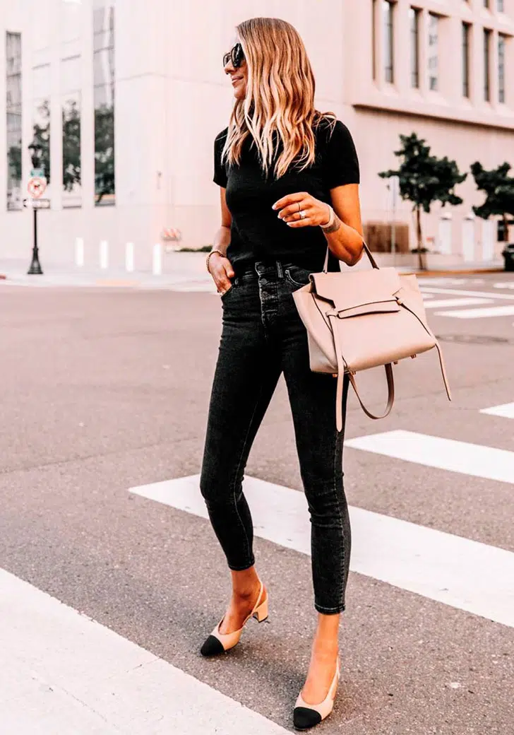 Девушка в узких джинсах, черной футболке и двухцветных туфлях с ремешком на пятке