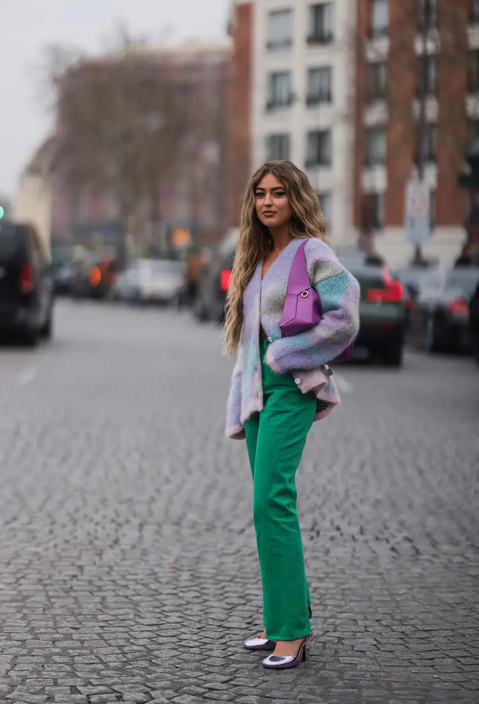 Девушка в зеленых джинсах, кардигане пастельного цвета и серебристых туфлях на каблуке