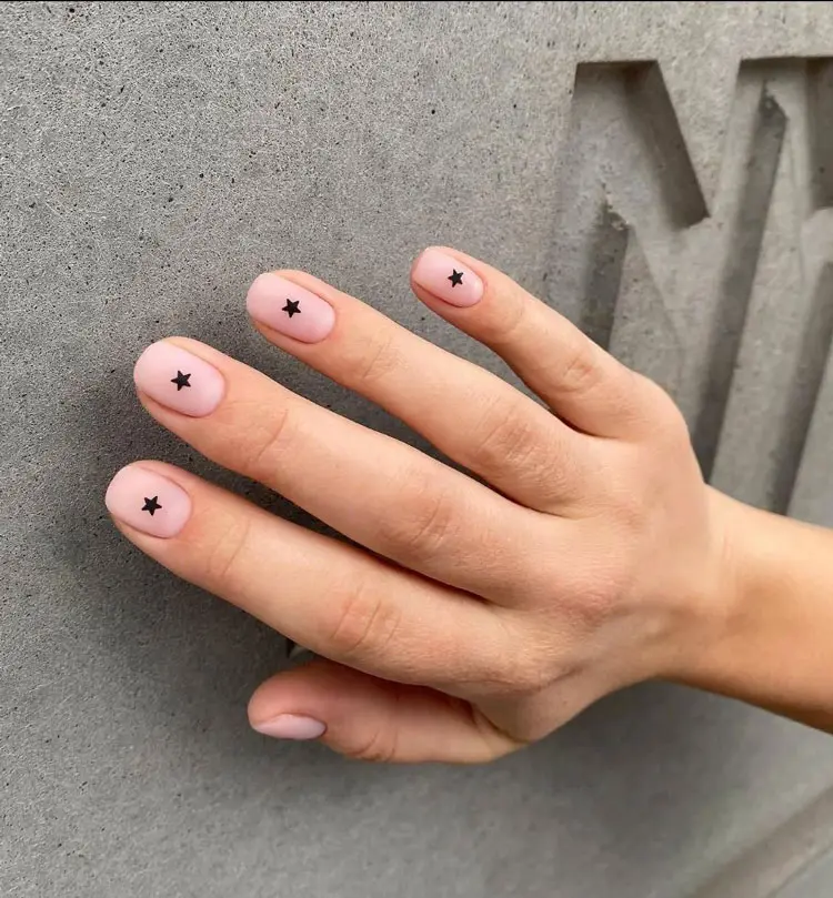 Натуральный матовый маникюр с минималистичными черными звездами на коротких ногтях