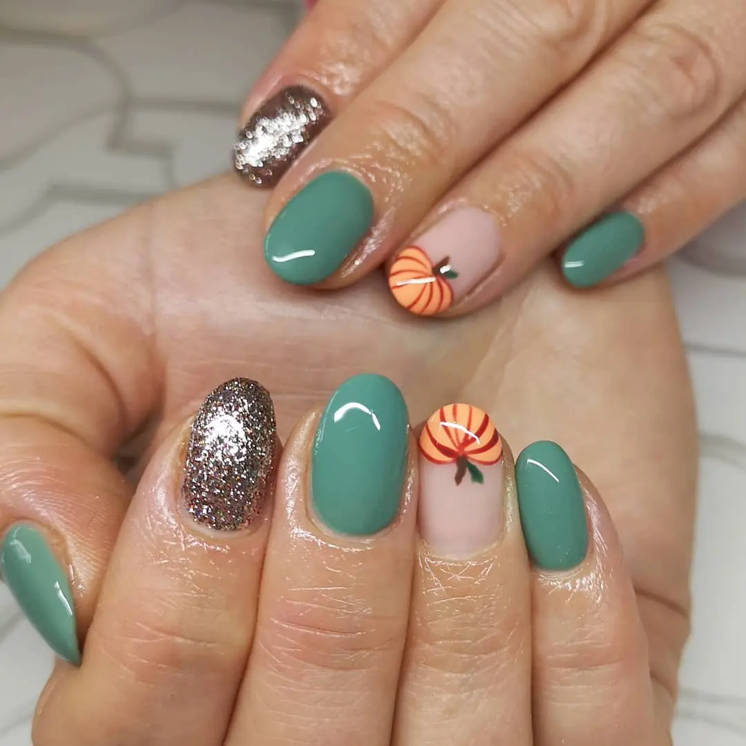 Осенний маникюр с серебристыми блестками и принтом тыквы на овальных ногтях
