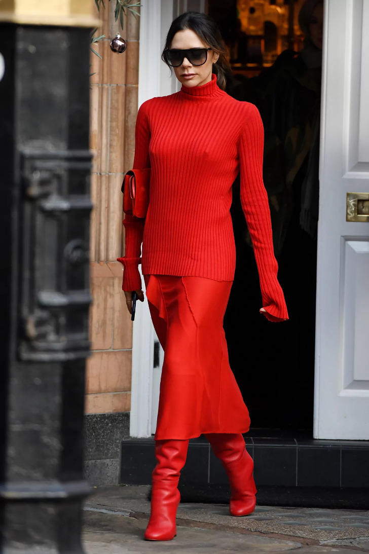Виктория Бекхэм в красной атласной юбке, свитере и красных сапогах на каблуке