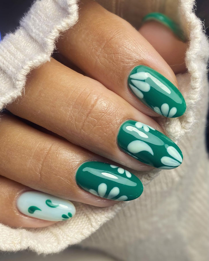 Темно зеленый маникюр с белым принтом на овальных ногтях