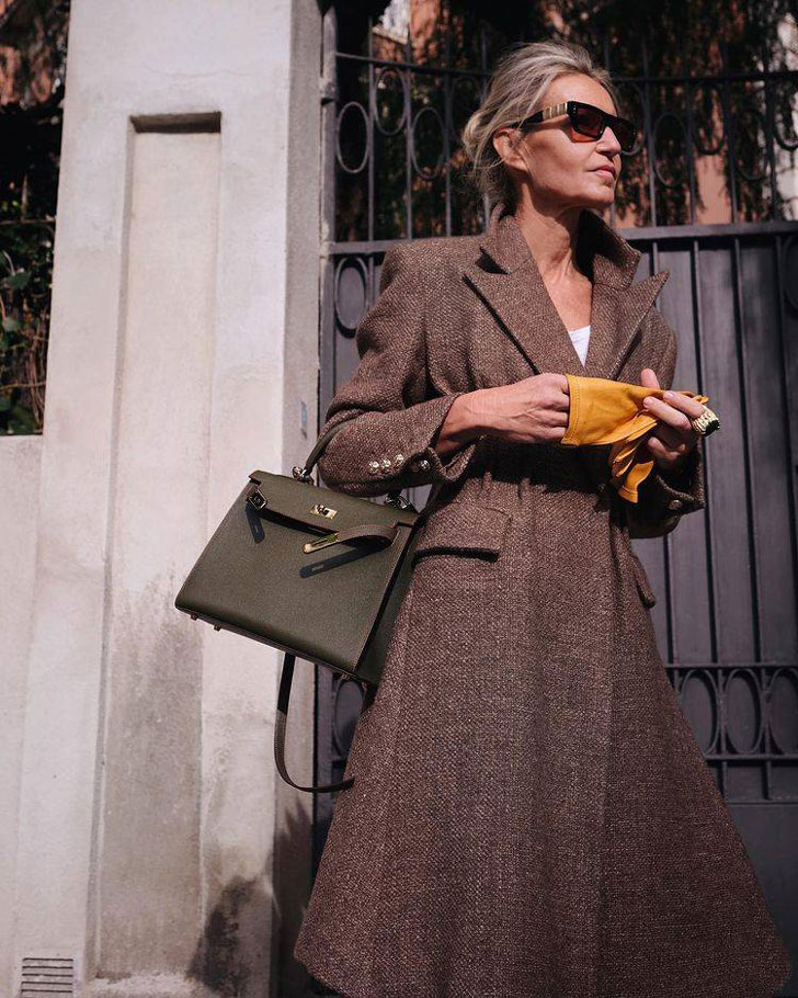 Женщина в коричневом пальто миди и классической сумкой