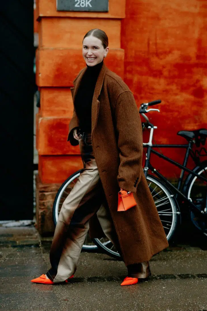 Девушка в бархатных брюках омбре, коричневом шерстяном пальто и оранжевых туфлях