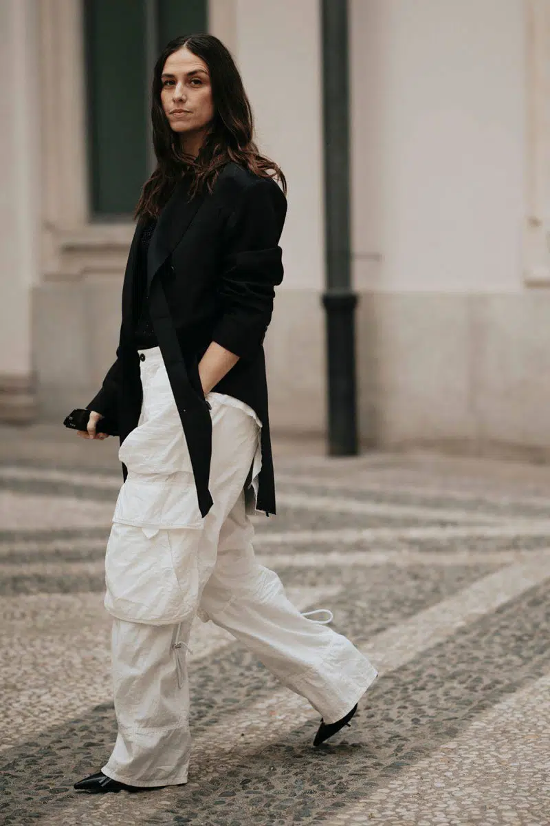 Женщина в белых брюках карго, черном блейзере и лакированных туфлях