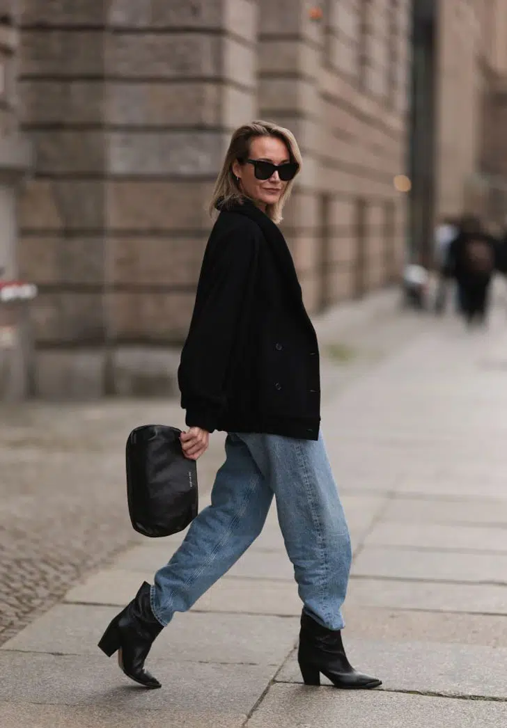 Девушка в мешковатых джинсах, черном пиджаке и ковбойских сапогах
