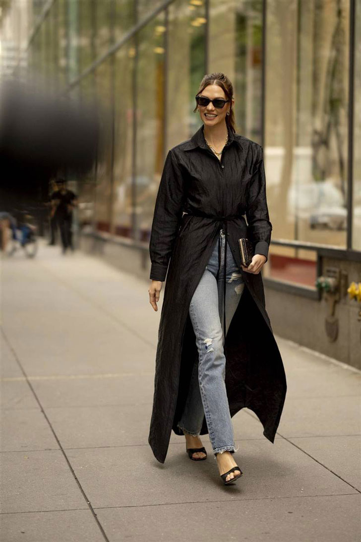 Карли Клосс в простых джинсах, черном платье-рубашке и сандалиях на каблуке