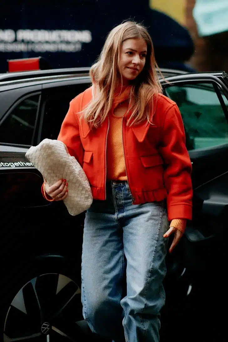 Девушка в свободных джинсах и укороченной оранжевой куртке