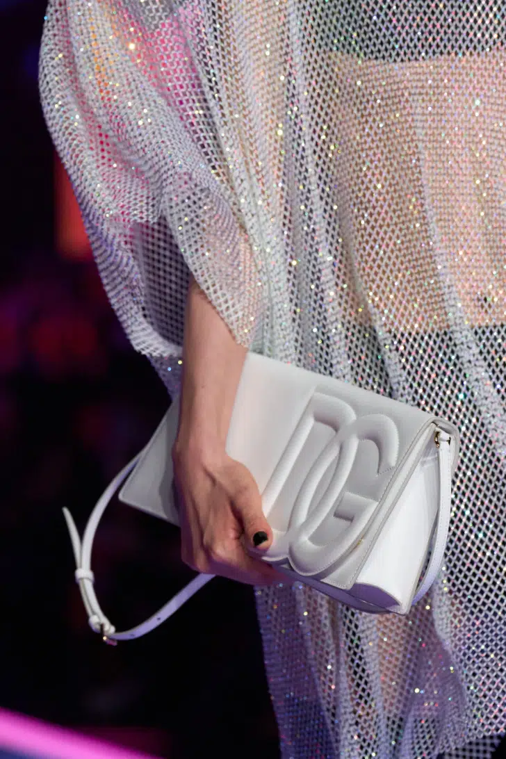 Модель с кремово-белой сумочкой с логопом от Dolce & Gabbana