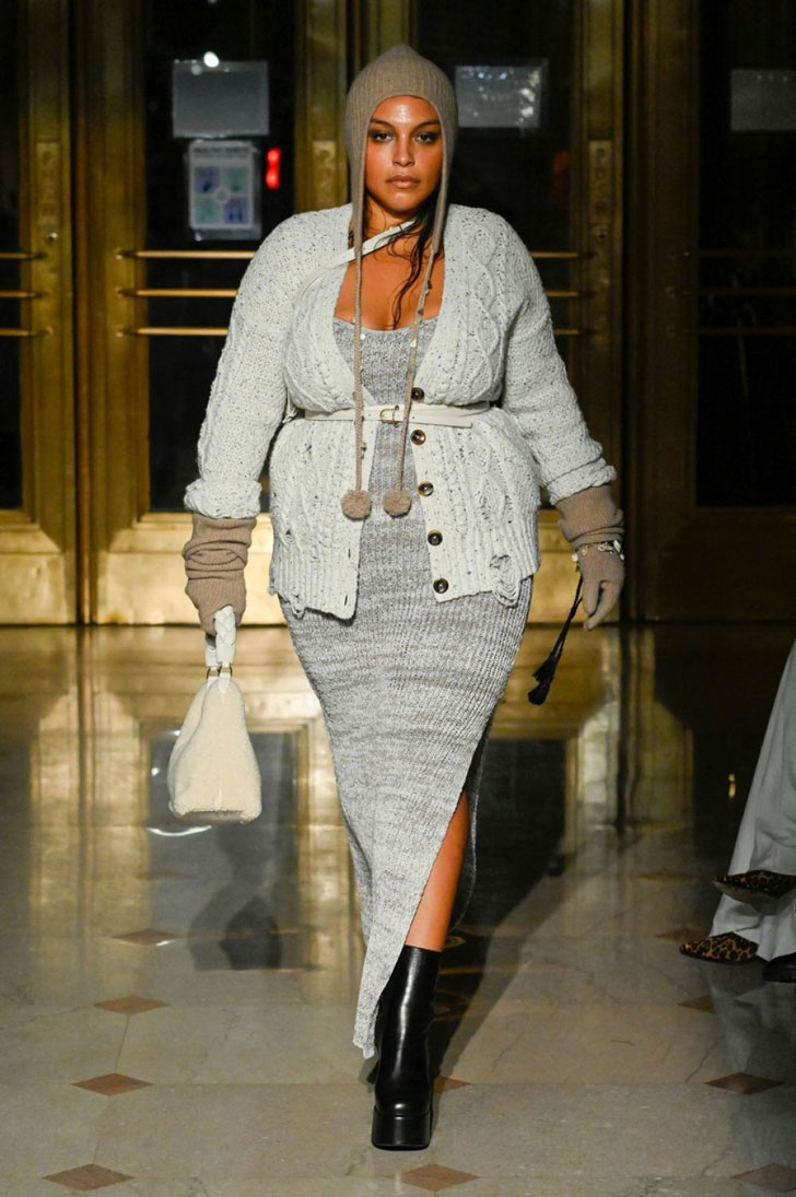 Модель в сером платье лапша и вязанном кардигане с ремнем на талии