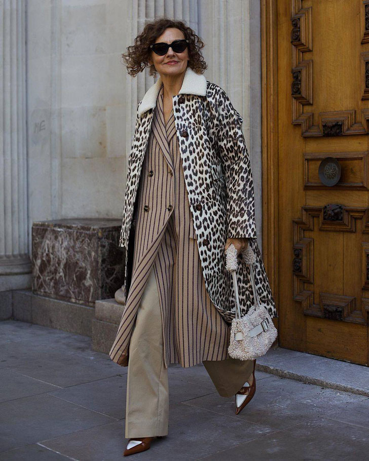 Женщина в бежевых брюках, пальто с леопардовым принтом и коричневых лоферах