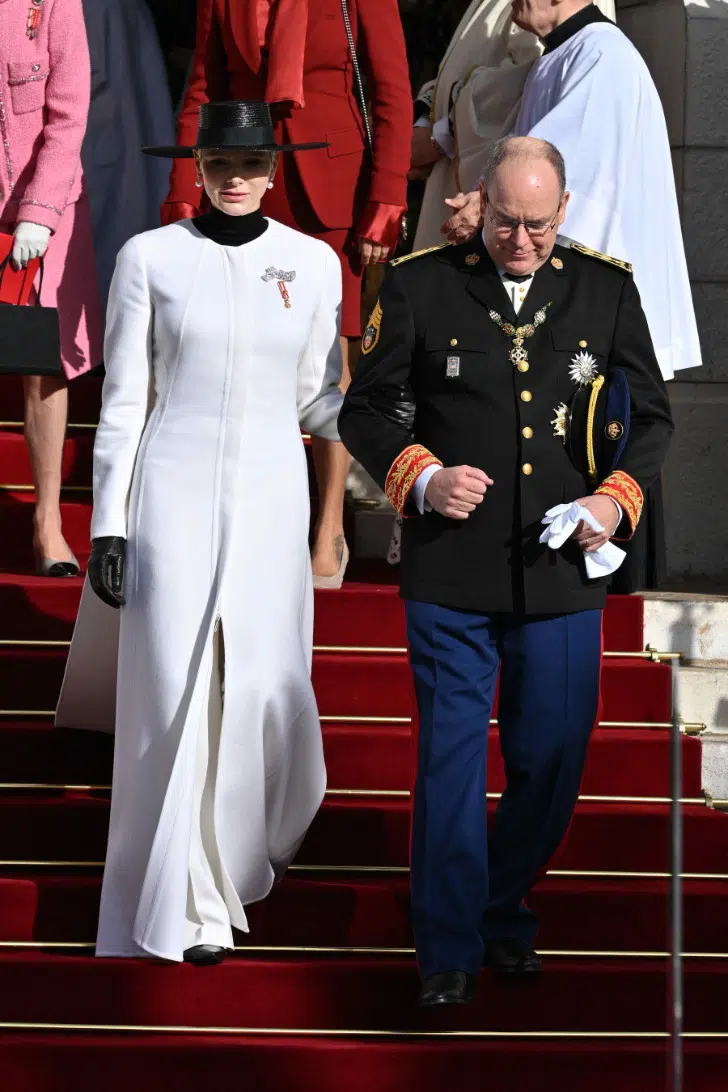 Принцесса Шарлен в длинном пальто, белых брюках и черной широкополой шляпе