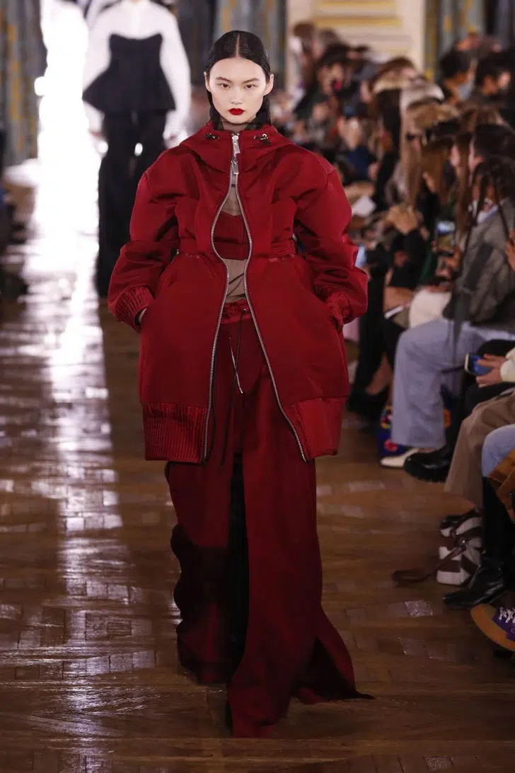 Модель в длинной красной юбке и куртке средней длины от Sacai