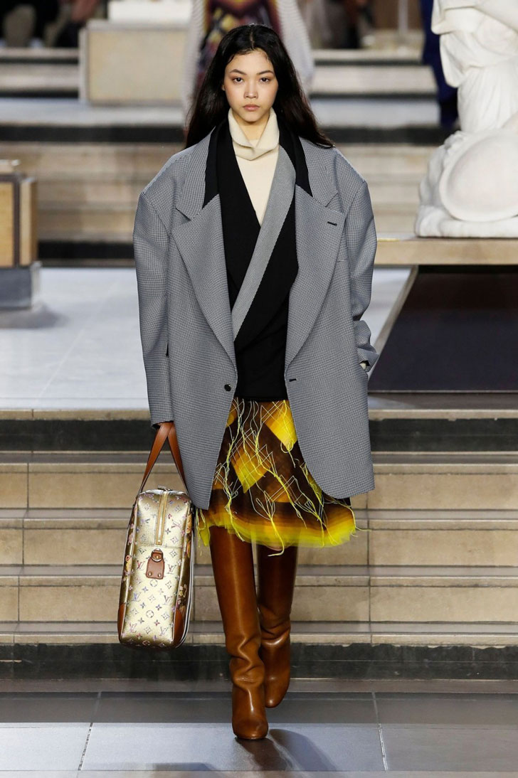 Модель в сером пальто оверсайз и высоких коричневых сапогах от Louis Vuitton