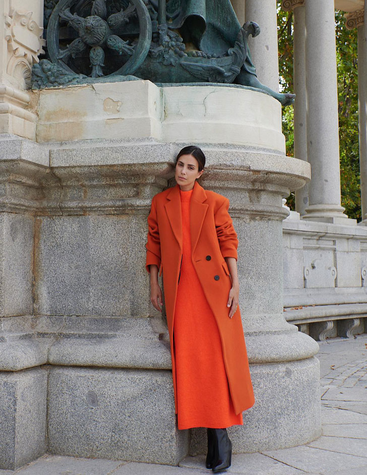 Алессандра де Осма в длинном вязанном платье, оранжевом пальто и черных сапогах