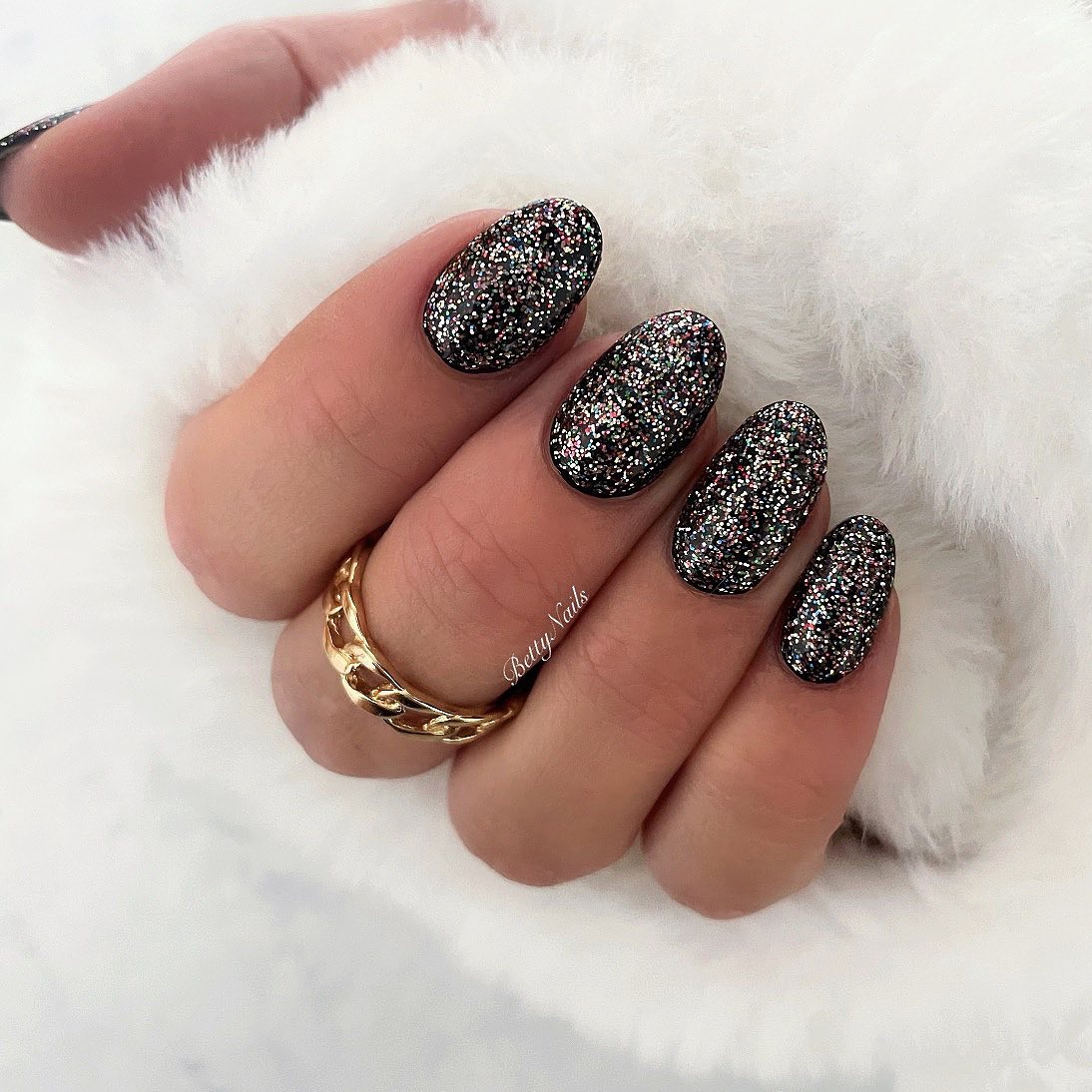 Черный праздничный маникюр с блестками на овальных ногтях средней длины
