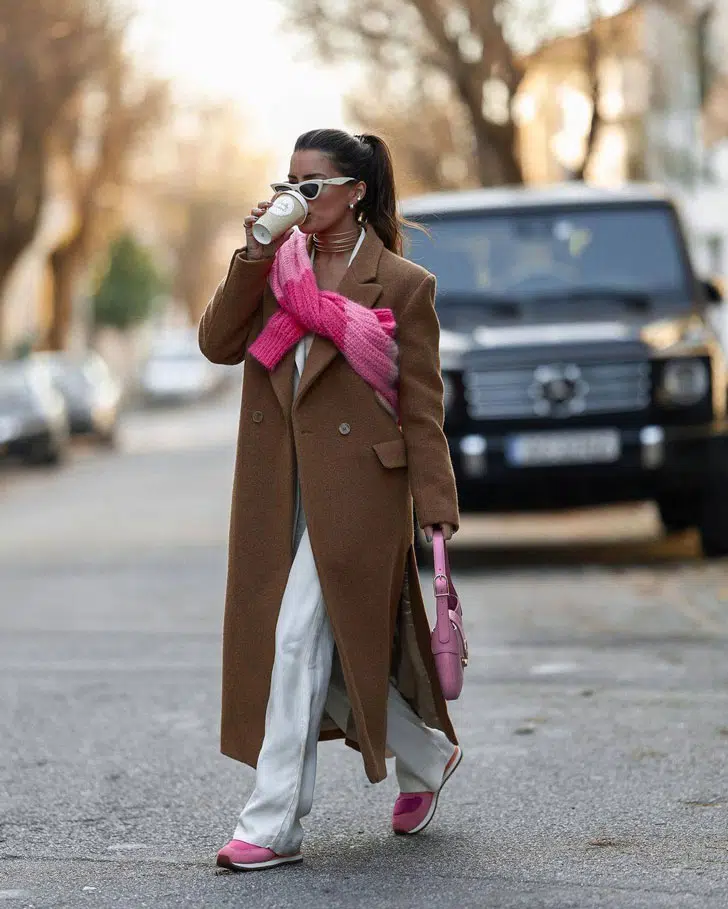 Девушка в коричневом пальто оверсайз, белых спортивных брюках и розовых кроссовках