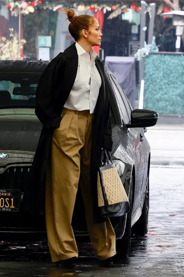 Дженнифер Лопес в широких брюках, длинном черном плаще и асимметричной рубашке