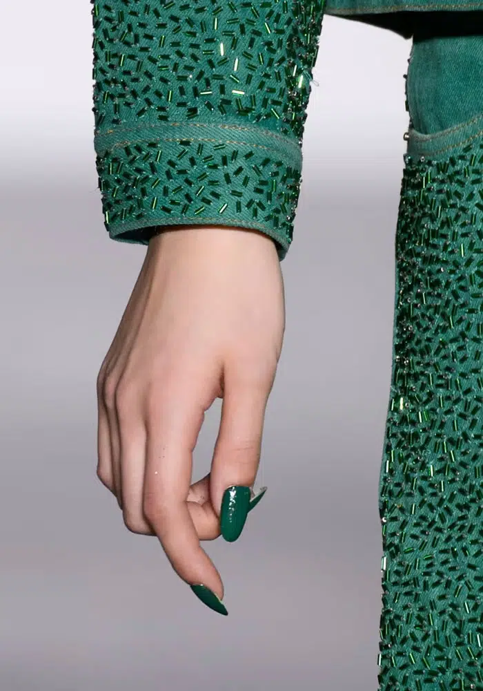 Модель с приглушенным зеленым маникюром на овальных ногтях средней длины