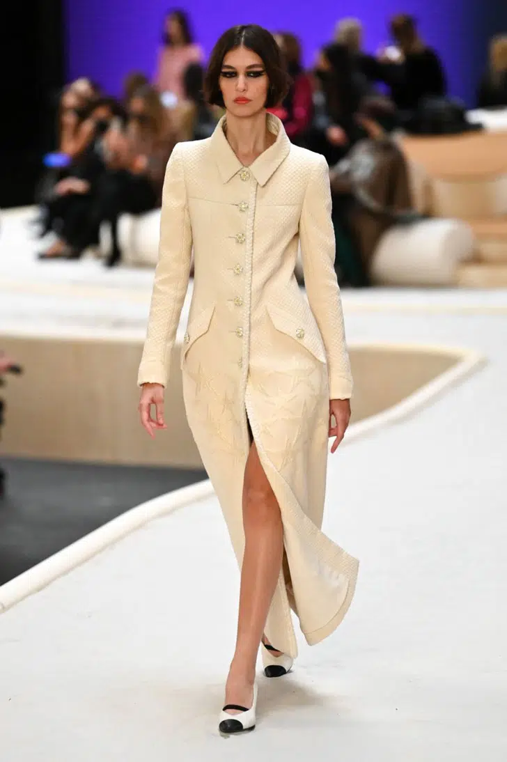 Модель в длинном бежевом пальто от Chanel