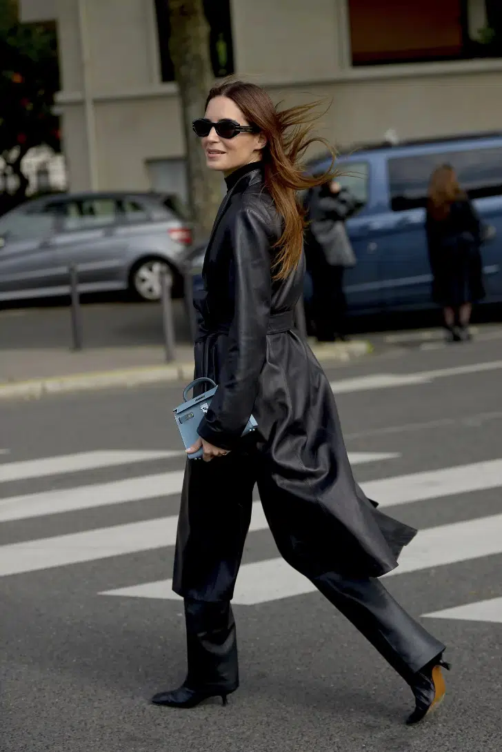 Девушка в кожаных брюках, черном плаще с поясом и ботильонах