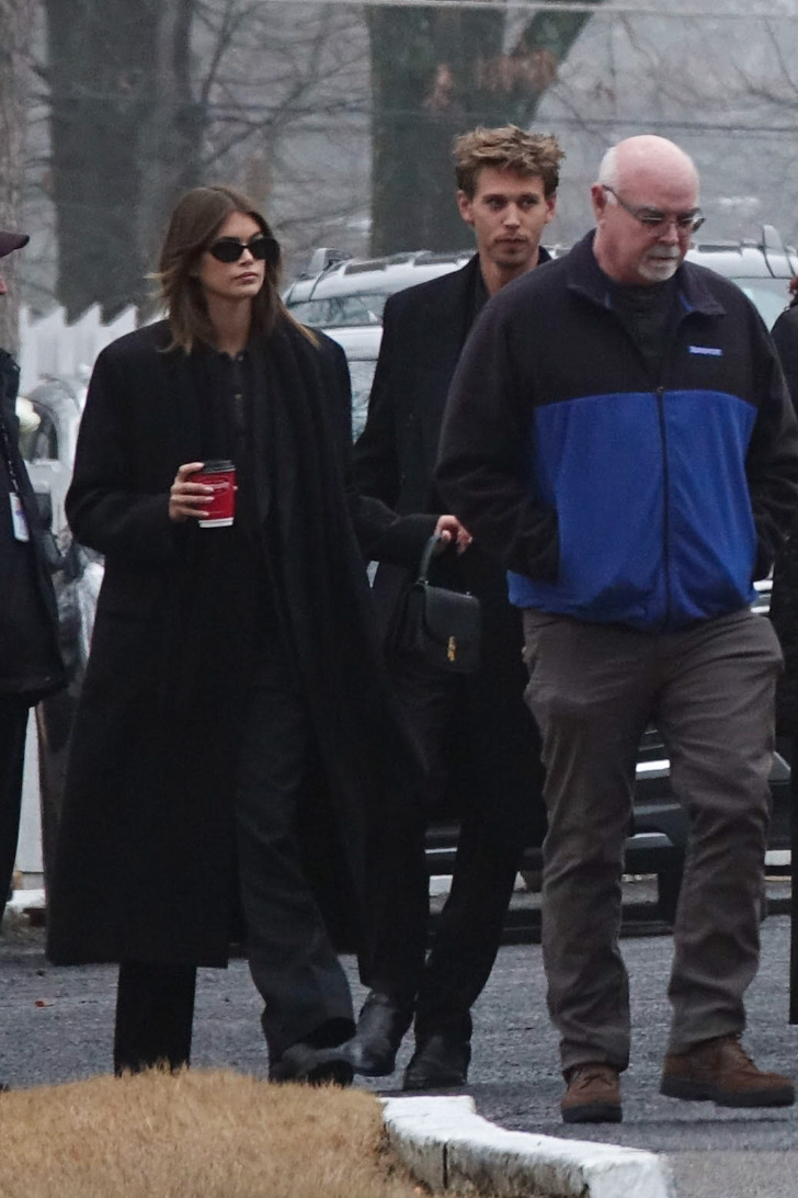 Кайя Гербер в черных брюках, пальто и рубашке