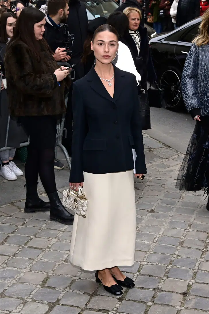 Sophia Roe в кремовой юбке и черном пиджаке перед показом Dior 2023