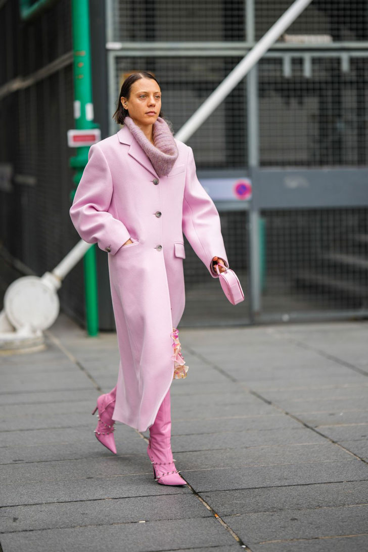 Девушка в прямом розовом пальто, свитере и розовых сапогах на шпильке