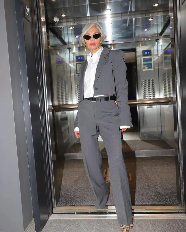 Грейс Ганем в серых офисных брюках, коротком жакете и белой рубашке