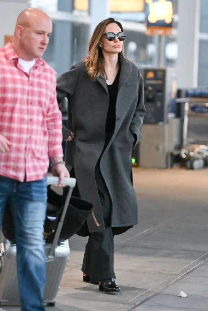 Анджелина Джоли в модных широких брюках, черных сапогах и пальто ниже колен