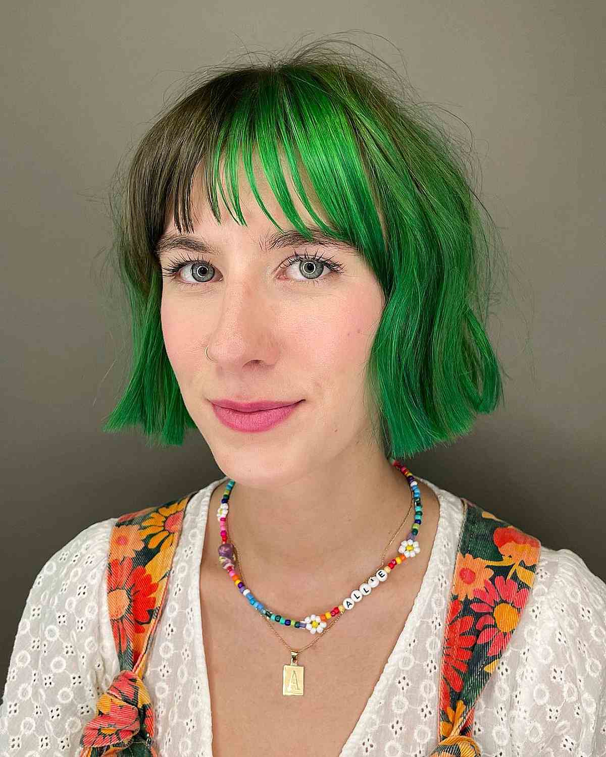 Девушка с текстурированной стрижкой боб с тонкой челкой на зеленых волосах