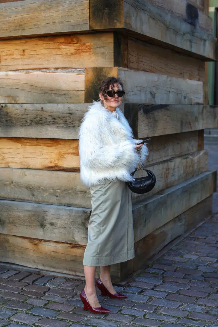Женщина в серой прямой юбке, меховой куртке и бордовых туфлях с полным каблуком